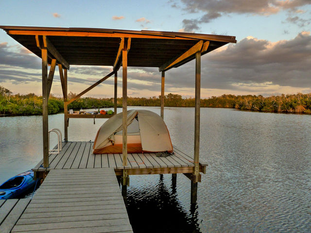 Tent on an elevated platform over water with a kayak attached
