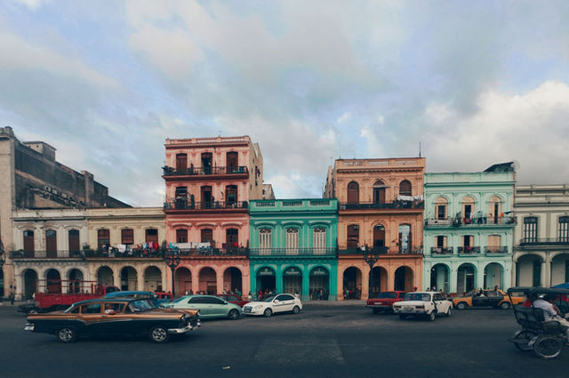 A vibrant street scene depicting colorful colonial buildings and classic cars in Havana, Cuba.