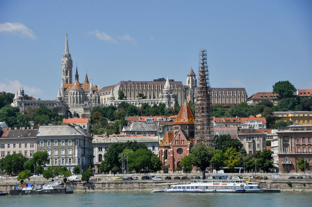 Scenic view of the Buda bank in Budapest, Hungary, featuring the magnificent Matthias Church and Fisherman's Bastion on the hill, overlooking the Danube river with the red-roofed Szilágyi Dezső Square