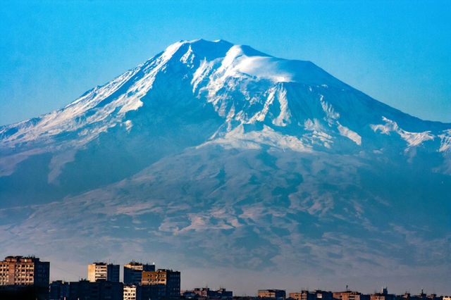 Snow-capped mountain looms over city buildings
