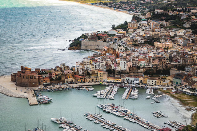 A picturesque aerial shot of a coastal town in Sicily, showcasing the marina and historic architecture.