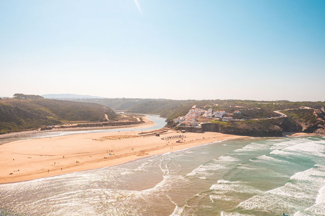Aerial view of a picturesque beach in Alentejo, Portugal with waves and cliffs on a sunny day.