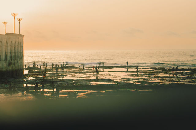 People enjoying a serene sunset at Casablanca beach with stunning ocean reflections.
