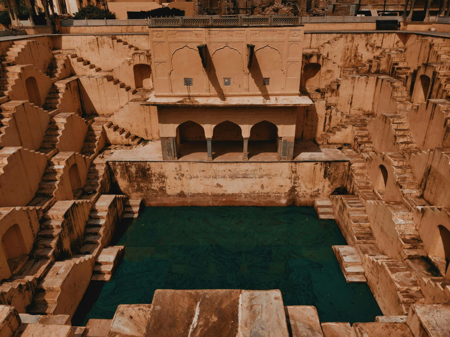An arcaded stepwell descending to still green water