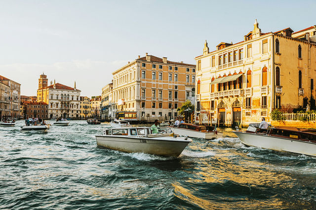 Bustling Venice canal with boats, capturing historic architecture at golden hour.