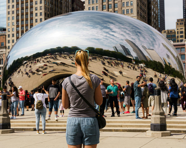 A woman stands before chicago's cloud gate sculpture.