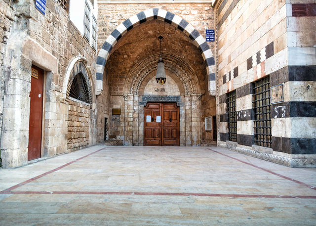 Intricate stone archway and historic door in Aleppo, showcasing traditional Middle Eastern architecture.