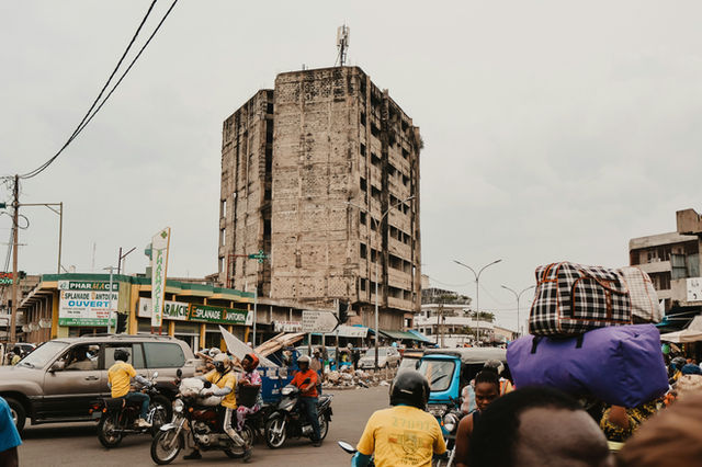 Busy street scene with a large, weathered building.
