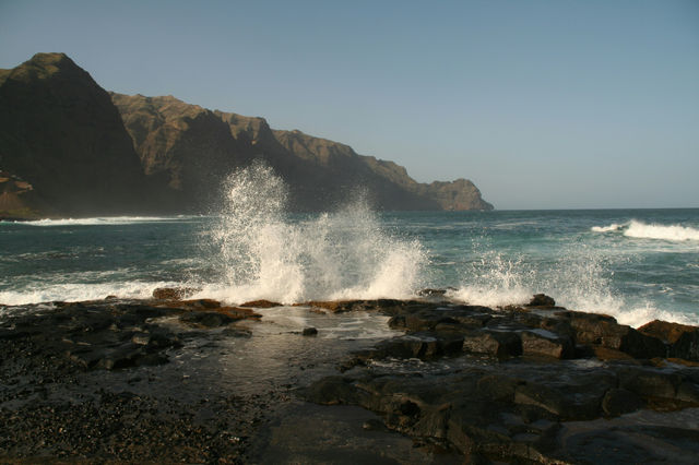a large wave hitting the rocks on the beach