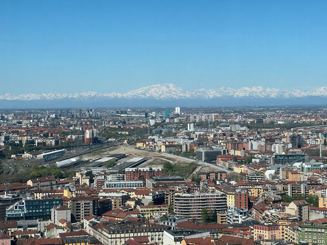 Stunning aerial view of Milan's urban sprawl with the snow-capped Alps in the background.