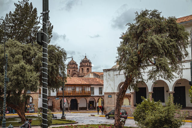 Charming view of a historical square in Cusco, Peru with colonial architecture and lush greenery.
