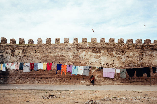 Colorful laundry hanging on ancient city walls in Essaouira, Morocco, showcasing daily life.