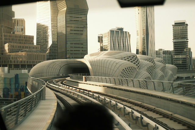 Futuristic cityscape with elevated train tracks and modern architecture.