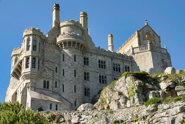Explore the stunning architecture of a historic castle in Cornwall, set against a vibrant blue sky.