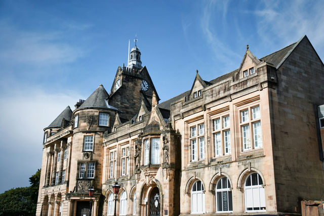 Historic stone building with clock tower against blue sky