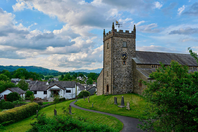 Charming stone church with clock tower in the tranquil Lake District, England. Ideal travel destination for nature and architecture lovers.