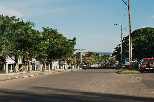 a red truck driving down a street next to trees