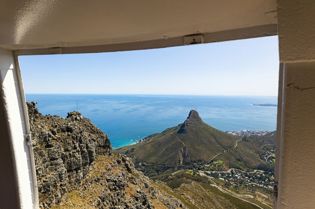 🏞️ View of Table Mountain from Cable Car Window – Cape Town, South Africa This photo frames Table Mountain through a wide glass window, with deep blue waters stretching between the viewer and the icon