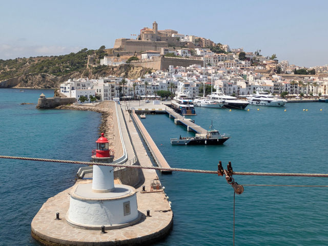 Stunning view of Ibiza harbor featuring a lighthouse with the historic old town in the background.