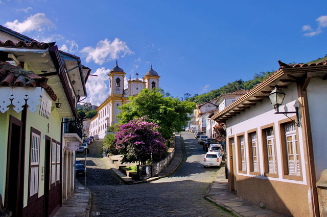 Scenic street in Ouro Preto featuring colonial architecture and vibrant trees.