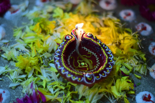 A single diya burning on marigold petals