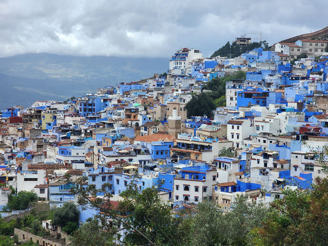 Discover the enchanting blue cityscape of Chefchaouen, Morocco, showcasing vibrant architecture nestled in lush hills.