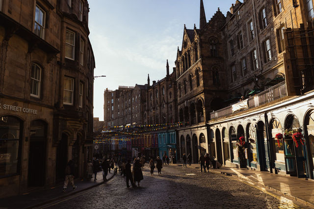 Victorian buildings and a bustling street scene captured in Edinburgh, Scotland, illuminated by golden sunlight.