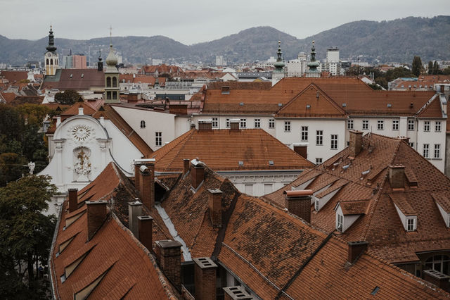 Explore Graz's charming old town with distinctive red tile roofs and historic architecture in this aerial view.