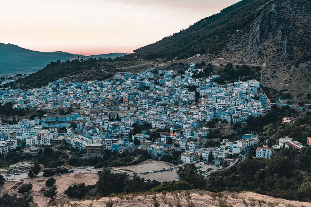 Stunning aerial view of Chefchaouen city with its blue buildings nestled against the hills at dusk.