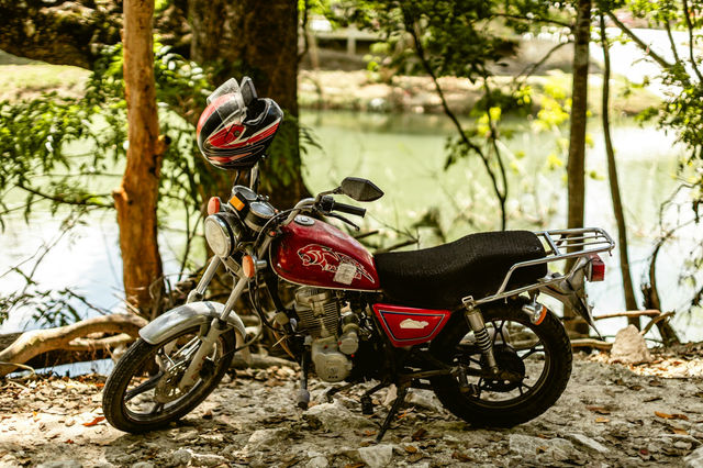 A red motorcycle is parked by the water