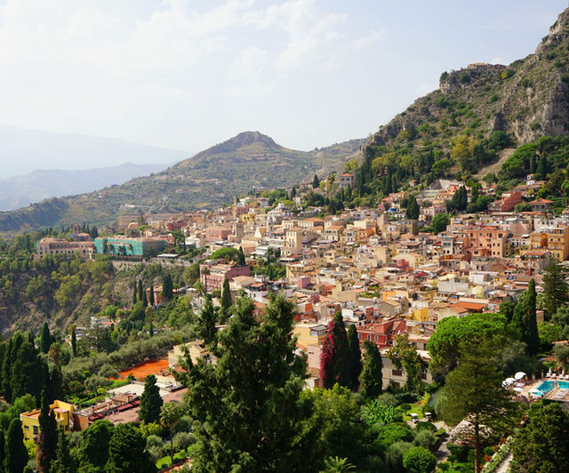 Scenic aerial view of Taormina, Sicily, showcasing vibrant buildings and lush greenery.