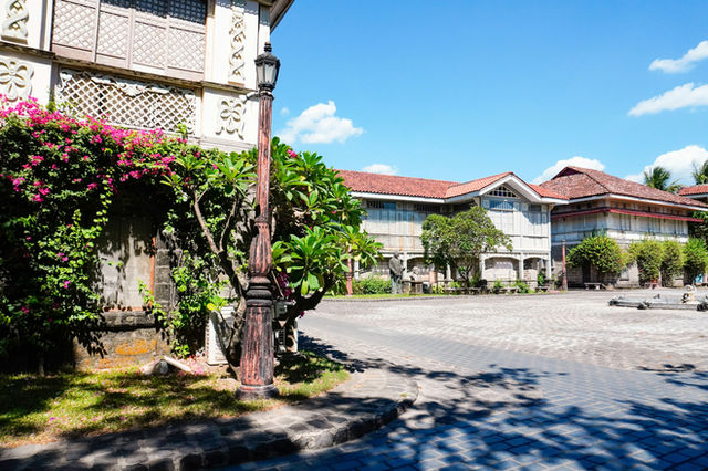 Historic buildings and a lamppost in a sunny courtyard.