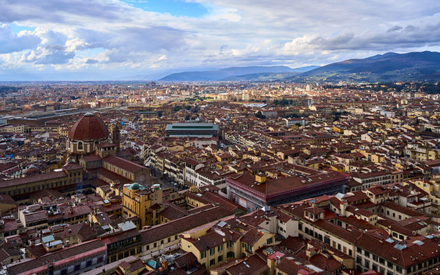 Aerial shot of Florence cityscape with historical architecture and distant hills.