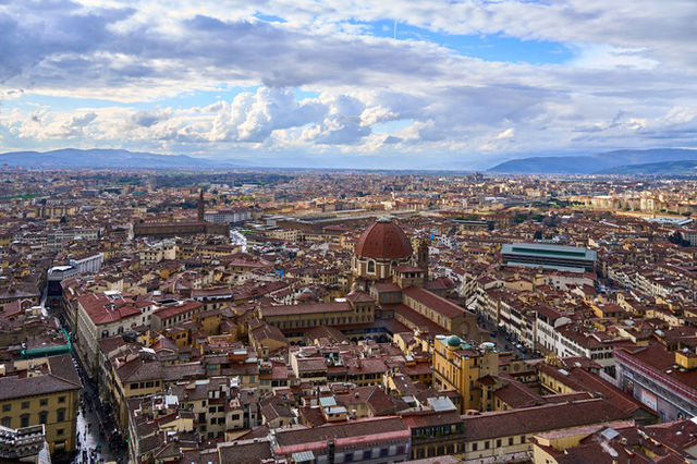 Captivating aerial shot of Florence, showcasing Il Duomo under expansive blue skies with clouds.