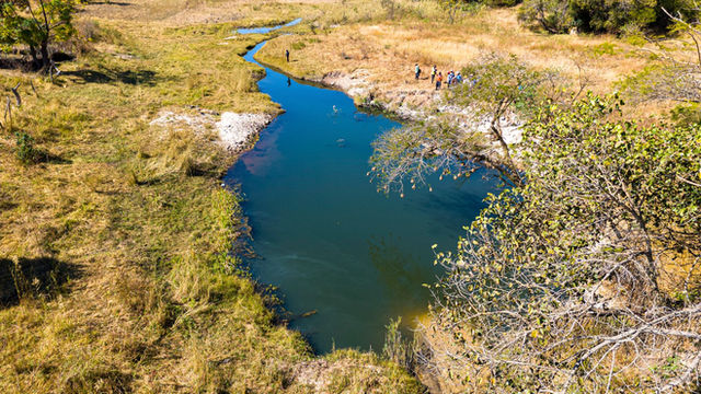 Aerial view of a tranquil river in Shurugwi, Zimbabwe with people on the riverbank.