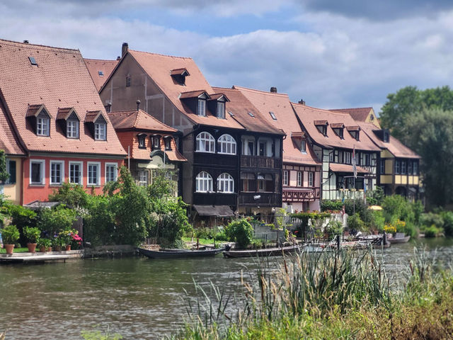 Historic half-timbered houses by the river in Bamberg, Germany, on a sunny day.