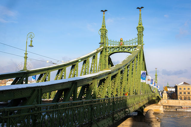 Green bridge covered in snow under a blue sky