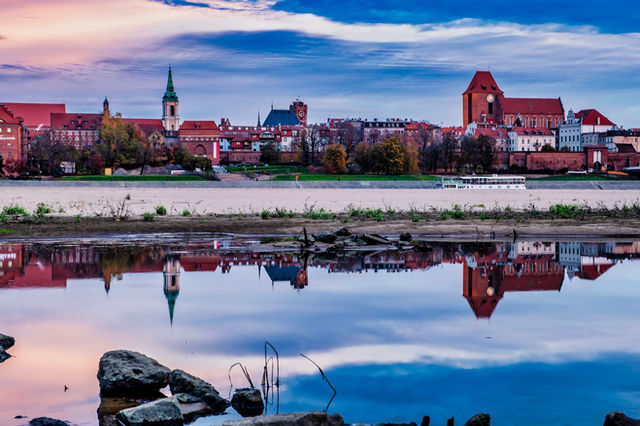 Captivating view of Toruń's medieval architecture reflecting in the Vistula River at dusk.
