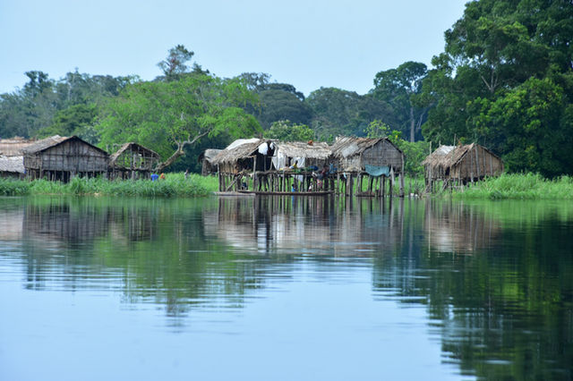 Stilt houses on a calm river surrounded by greenery