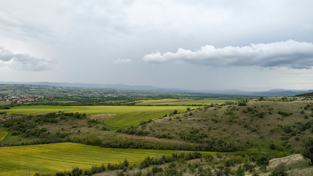 A view of a green field and a town in the distance