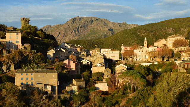 Picturesque view of the village of Nonza in Corsica, France, basking in the warm glow of sunset.