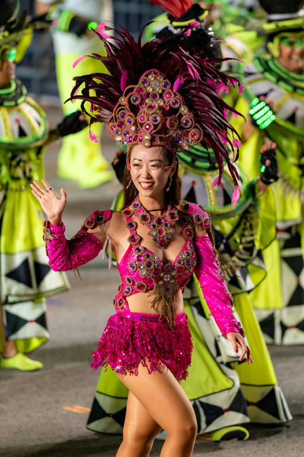 Magenta sequins and burgundy plumes, waving from the procession