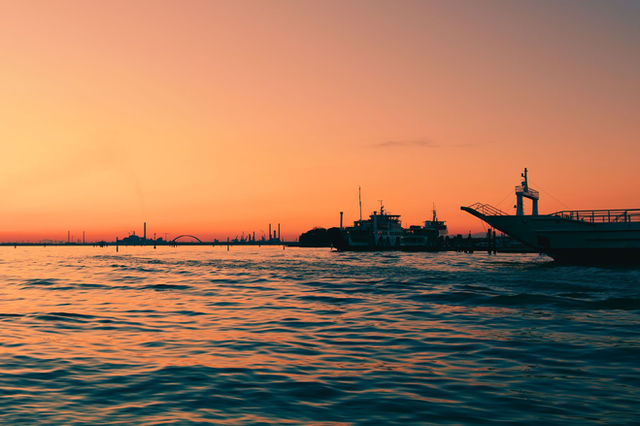 Capture the enchanting Venice sunset, reflecting over calm waters with moored boats.