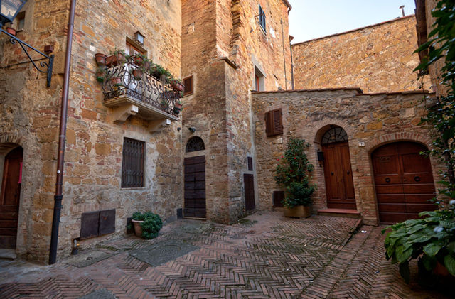 Picturesque stone alley with balconies and doors in Pienza, Tuscany, Italy.
