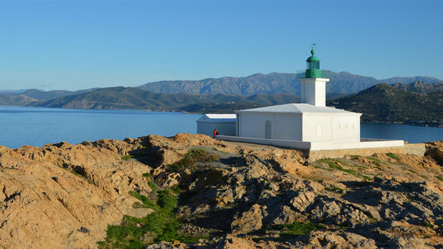 Stunning view of a lighthouse atop rocky cliffs in L'Île-Rousse, Corsica, France.