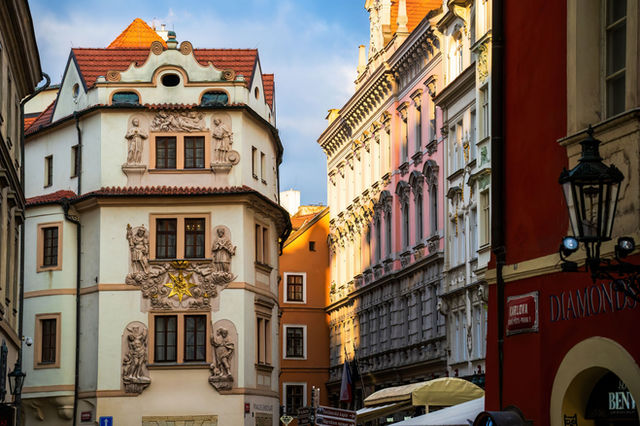 Charming street view of historic architecture in Prague city center, showcasing ornate facades in golden sunlight.