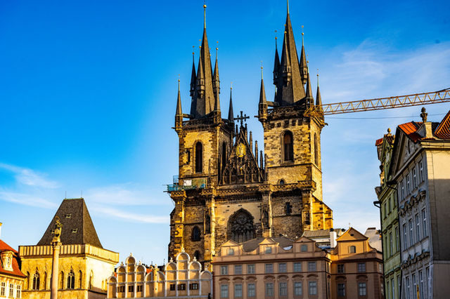 The stunning Gothic spires of Týn Church rise against a clear blue sky in Prague.