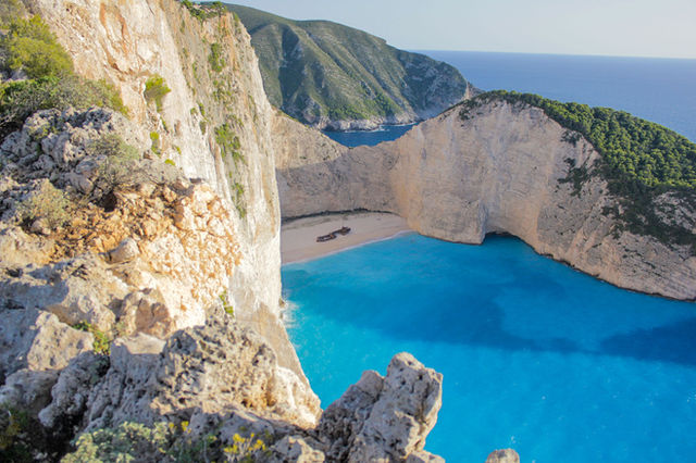 Stunning cliffside view of Navagio Beach's turquoise waters and sandy cove in Zakynthos, Greece.