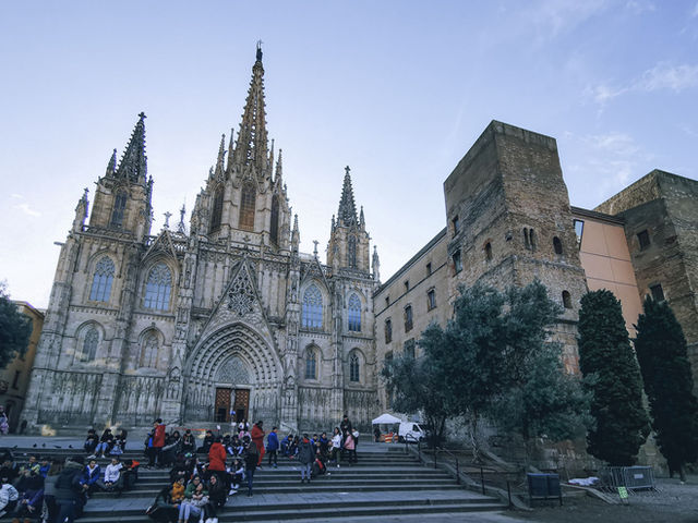 Stunning gothic cathedral facade in Barcelona with people on steps during daytime.