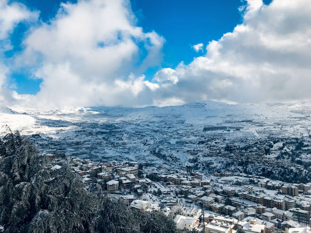 A picturesque view of a snowy town in Lebanon under a bright blue sky.
